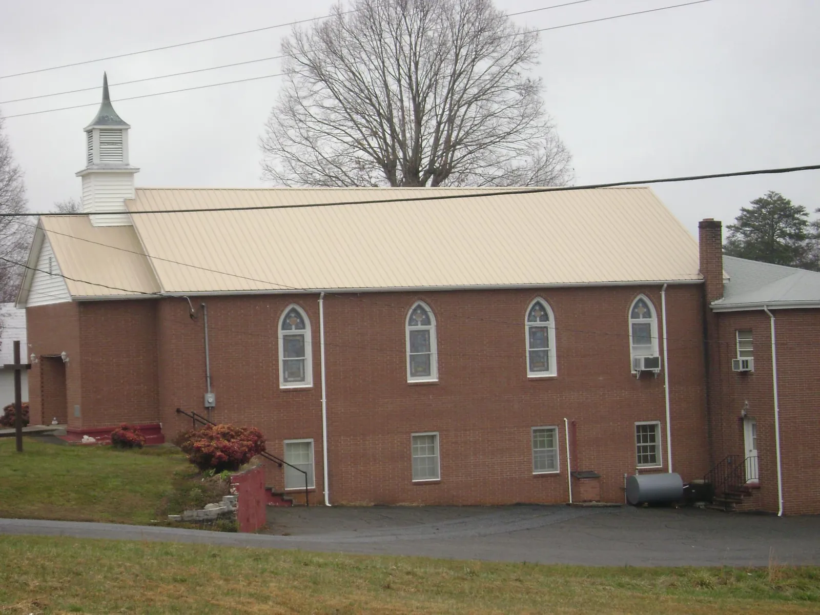 New tan metal roof on a brick church with a white steeple in Irvington