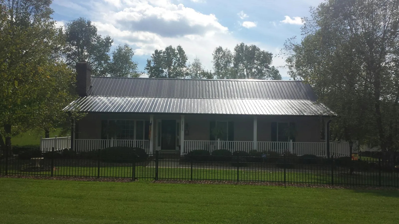 Gray metal roof on a brick ranch with a full width front porch — Gutter Guard Installation work by our crew in Irvington