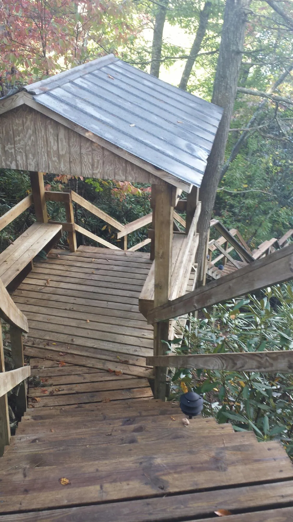 Metal roofed shelter over wooden steps on a wooded walkway — Skylight Repair & Installation work by our crew in Irvington